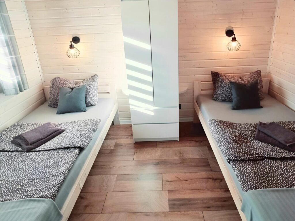 Domek z psem nad morzem. Przytulna sypialnia z drewnianymi akcentami i miękkim oświetleniem – idealne miejsce na relaks w Patkachatka