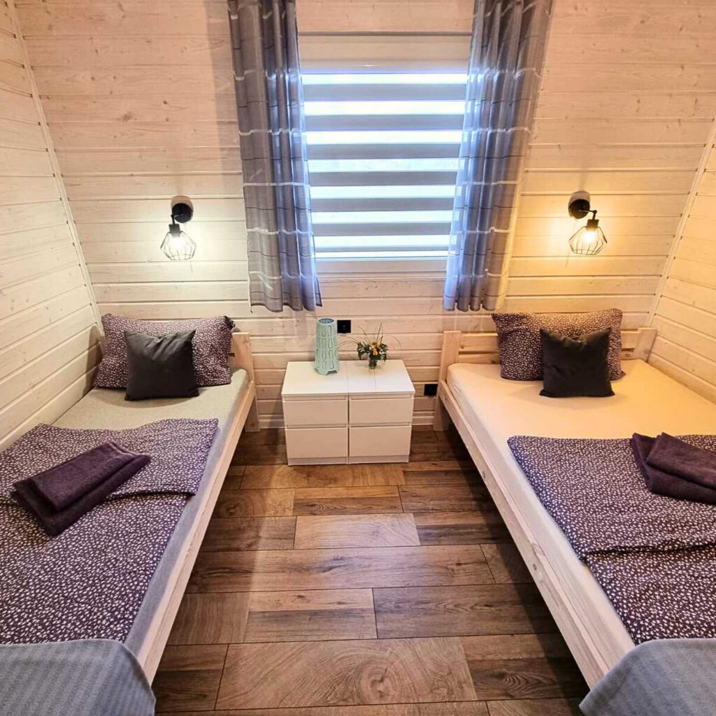 Weekend z psem nad bałtykiem. Stylowa sypialnia z drewnianą ramą łóżka i delikatnym oświetleniem – oaza spokoju w Patkachatka